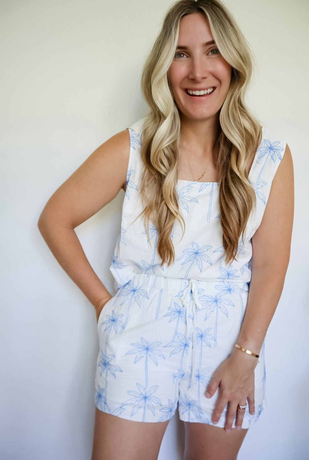 Woman wearing a white set with blue floral pattern against a plain background