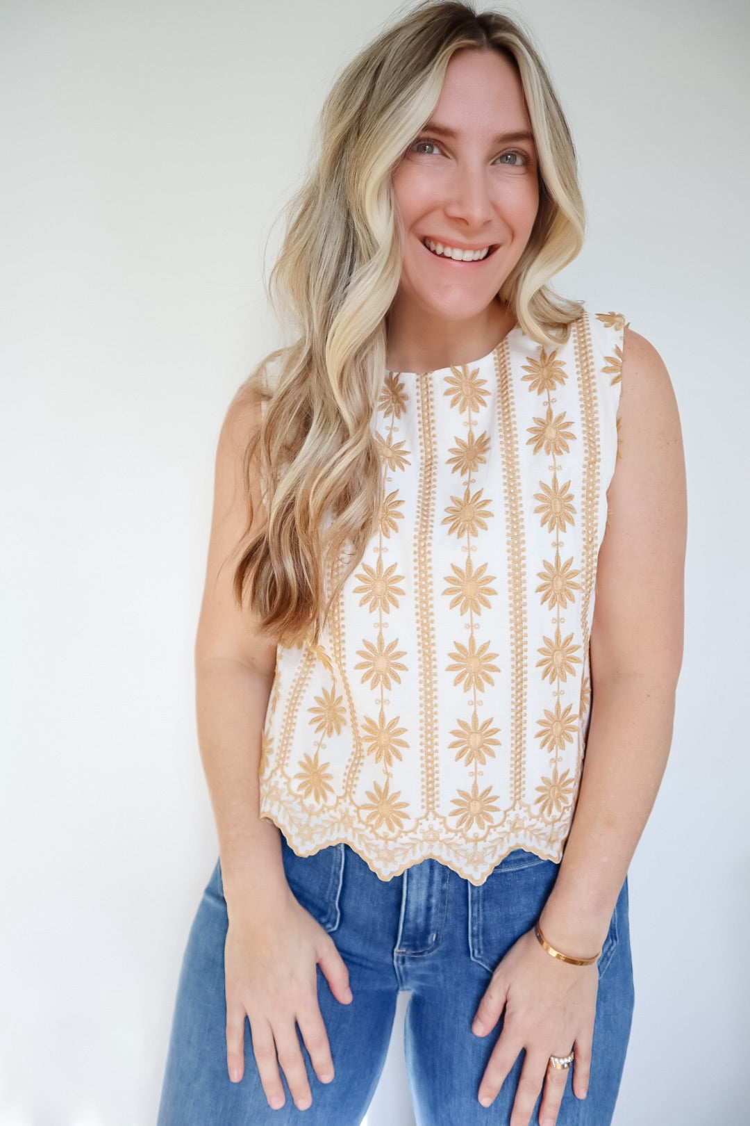 Woman wearing a sleeveless top with a floral pattern against a white background